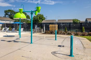 A playground with a water spray feature and a blue pole.